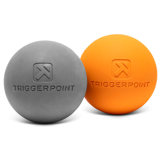 Gray and orange massage balls rest on a white surface in a fitness environment