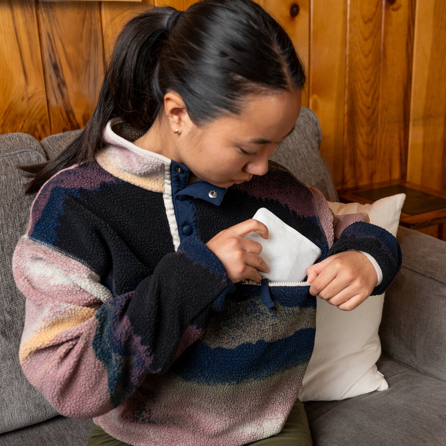 Girl with a sweater takes out tissues from her pocket on a sofa in a wooden room