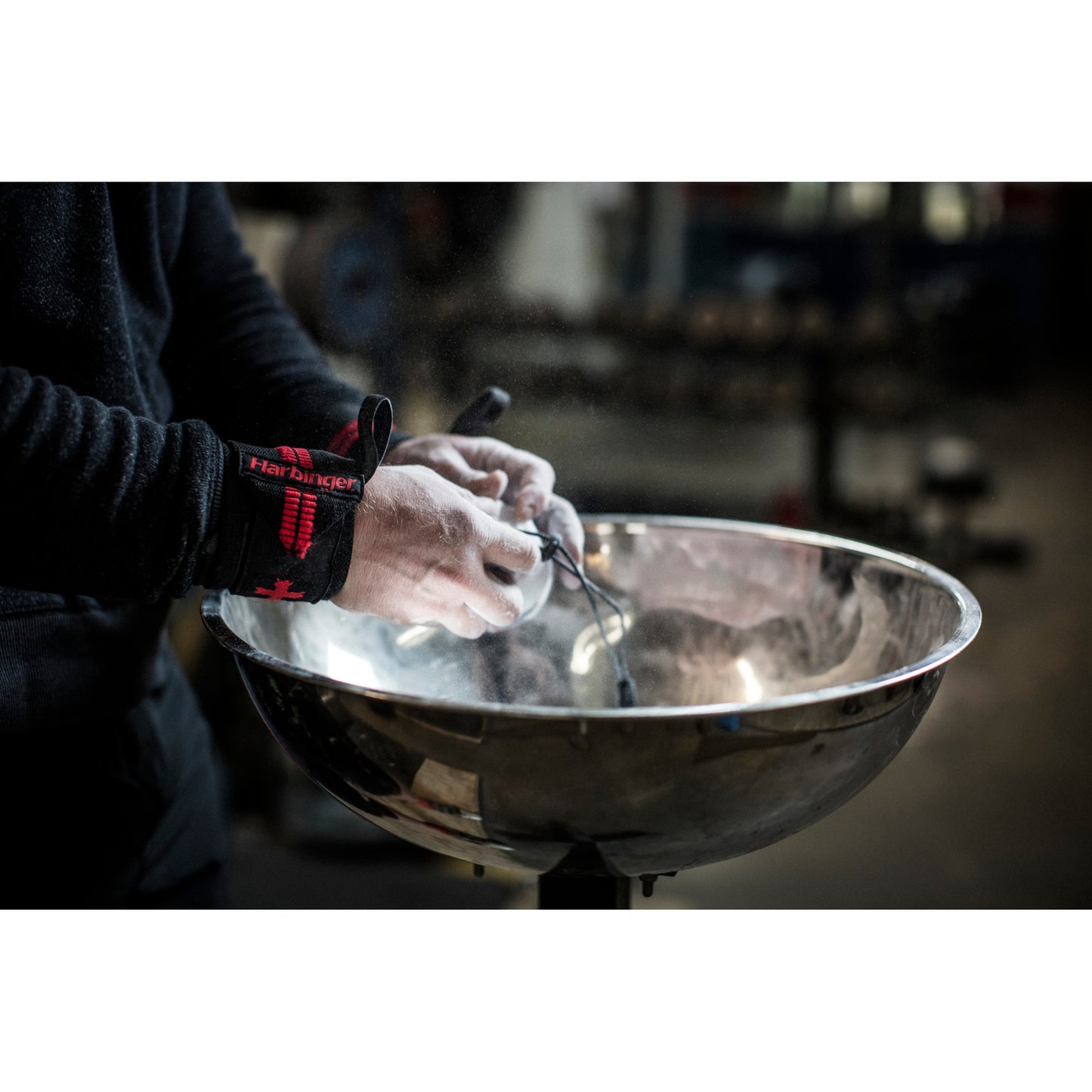 Hands apply chalk, preparing in a gym environment.
