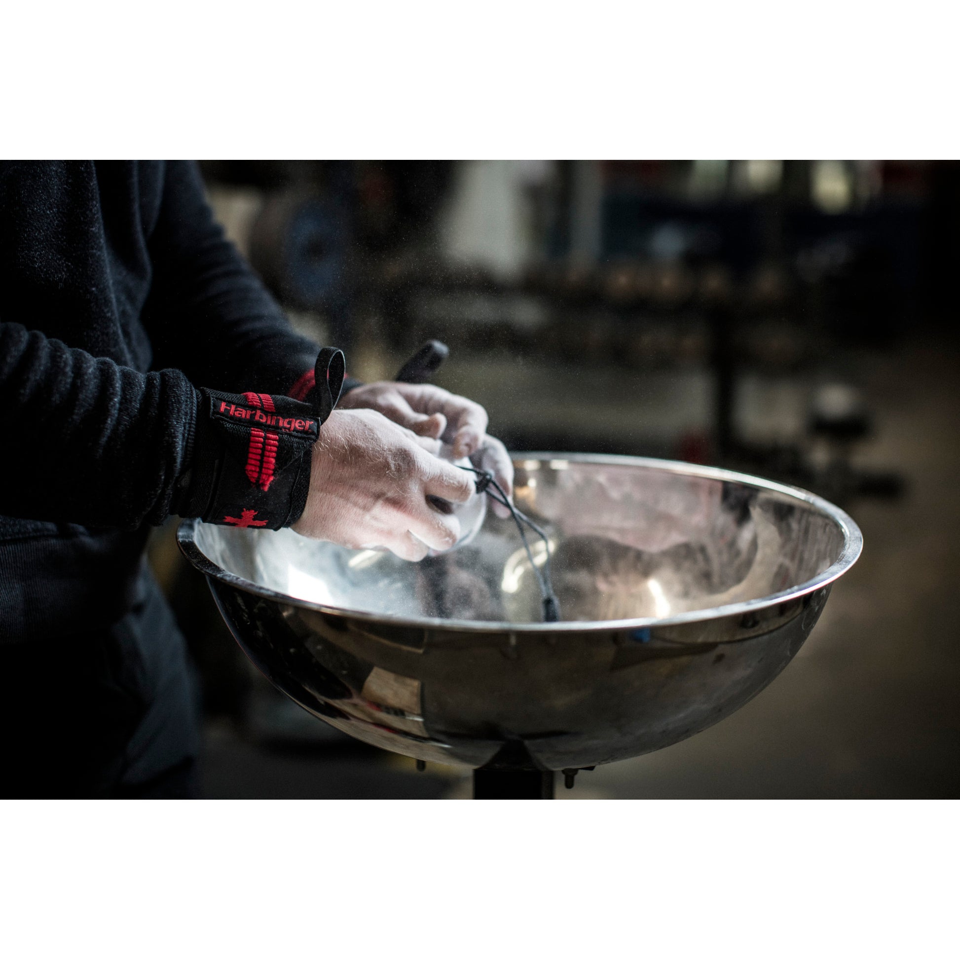 Hands apply chalk, preparing in a gym environment.