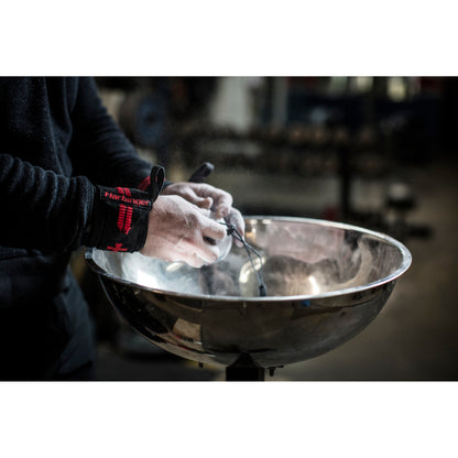 Hands apply chalk, preparing in a gym environment.