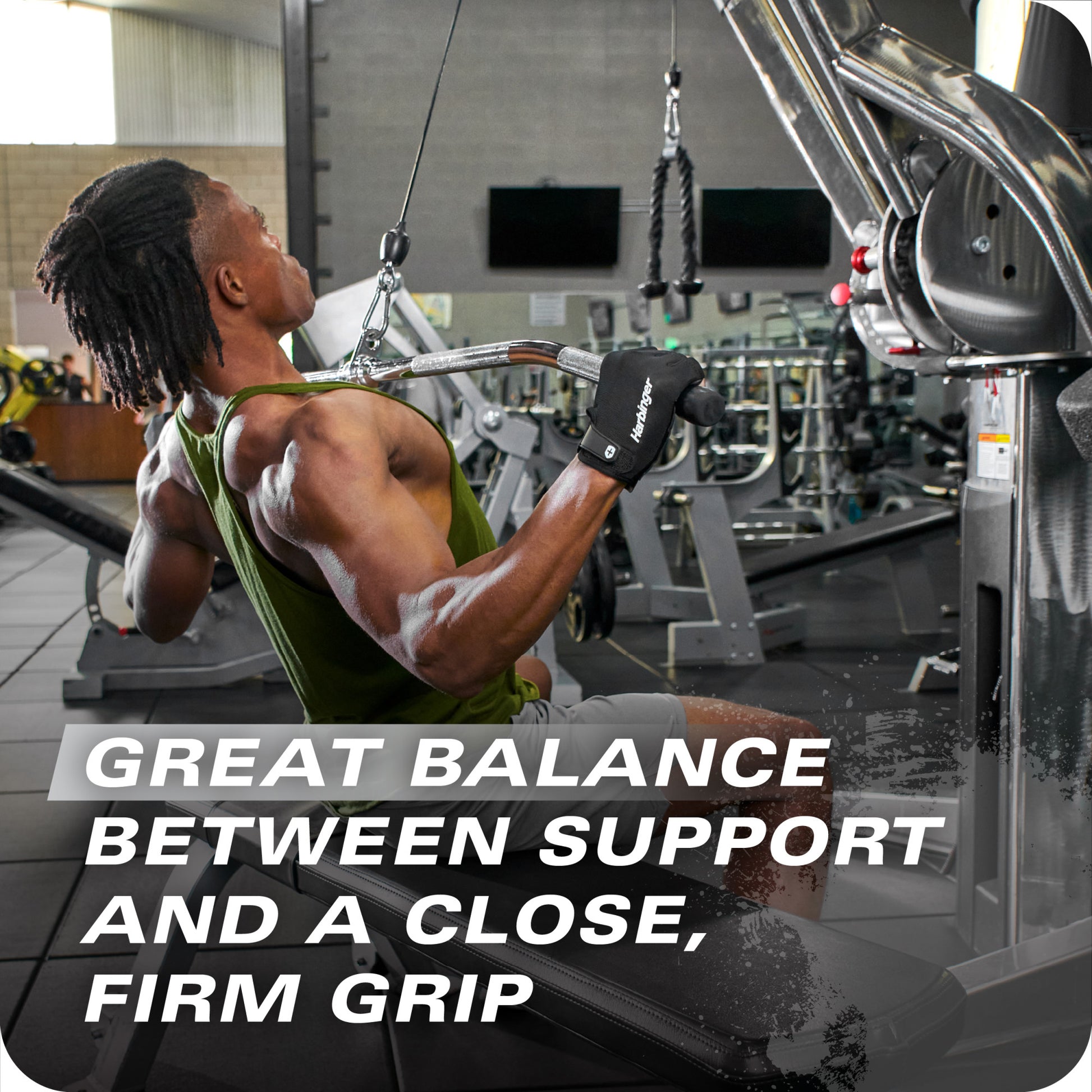 Man pulls cable on machine in gym amid fitness equipment and a wall with TVs