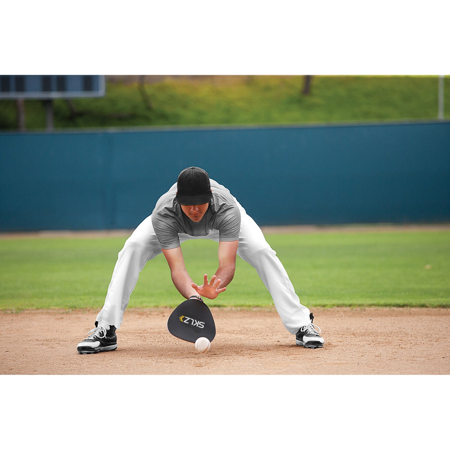 Baseball player reaches for ball on field during practice or game session