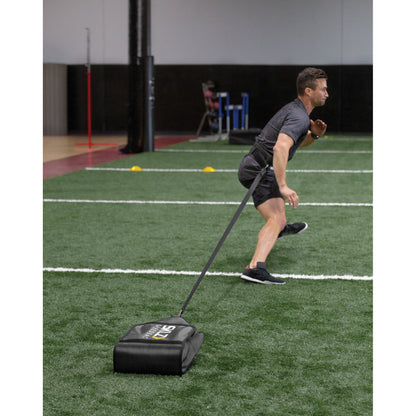 Man pulls weighted sled on indoor turf during training session