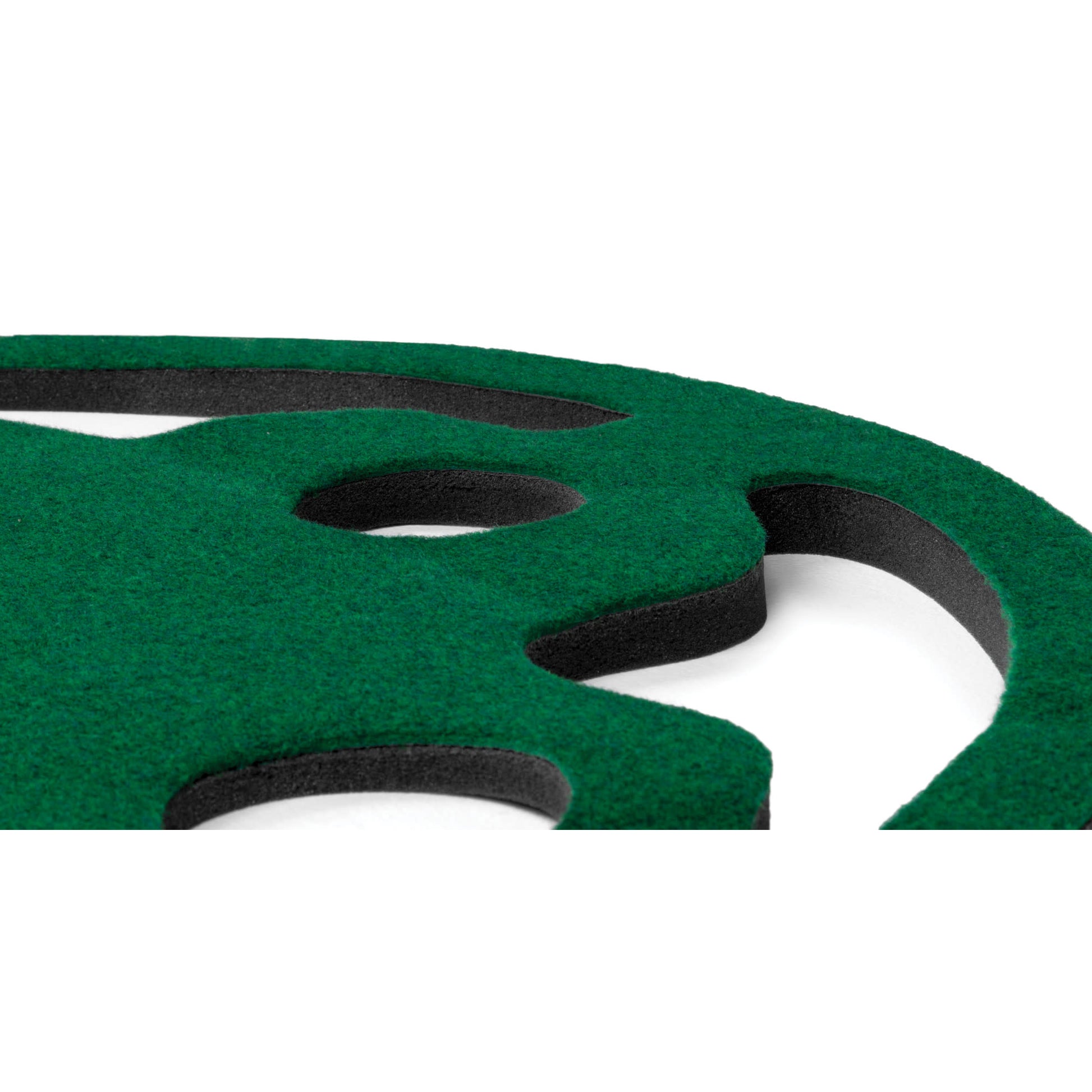 A green foam cutout with black inner layers rests on a white background