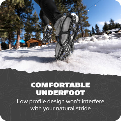 Boots walking on snowy ground surrounded by trees and a wooden cabin nearby.
