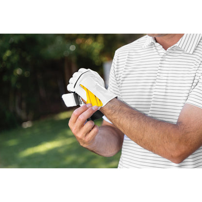 A person puts on a golf glove outdoors in a park or yard setting