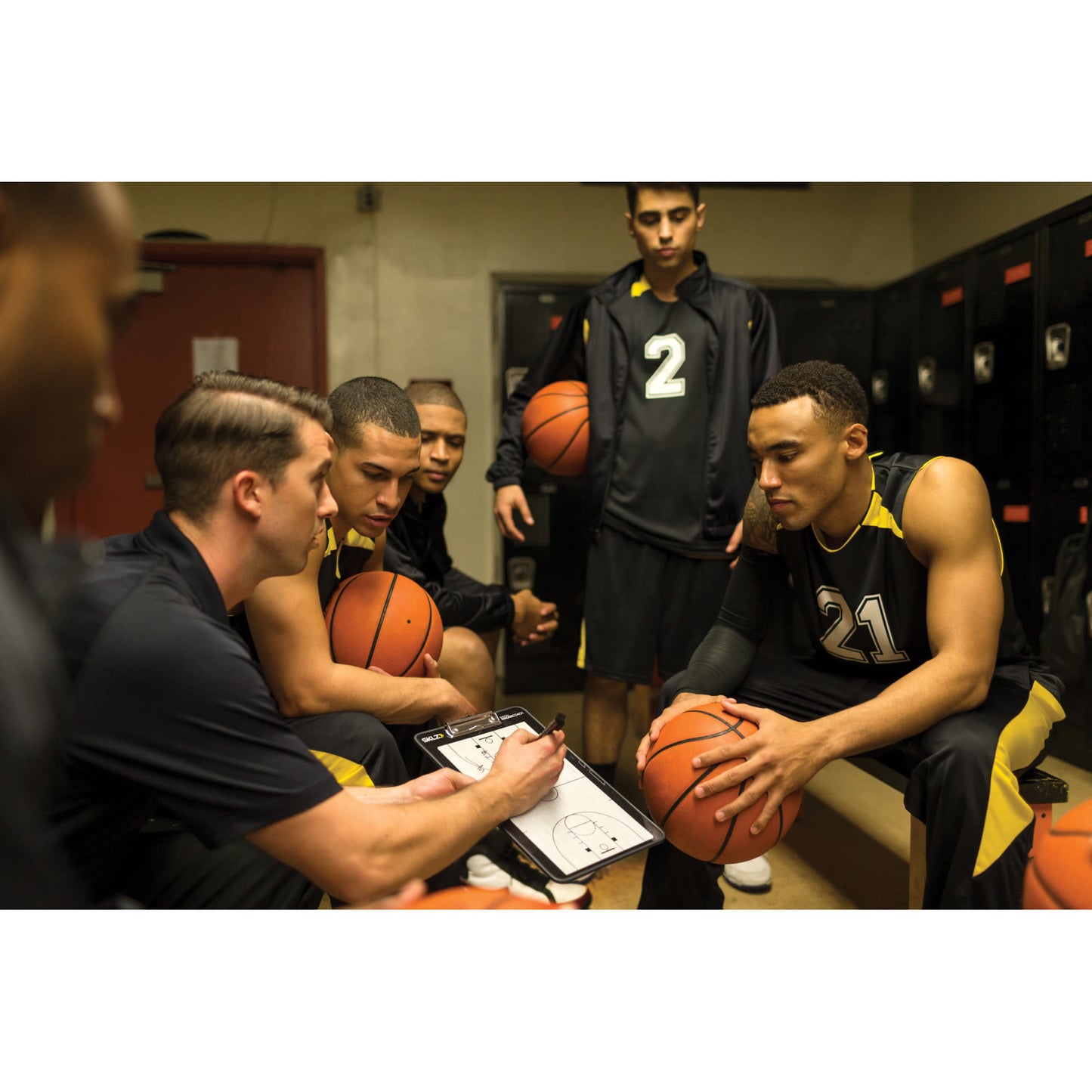 Basketball players listen to coach in locker room before game or practice