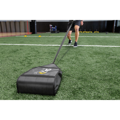 A person pulls a sled on artificial turf during training at an indoor sports facility