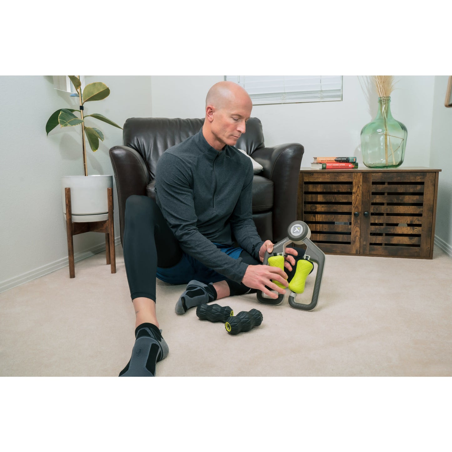 Man arranges exercise equipment on the floor in a living room.