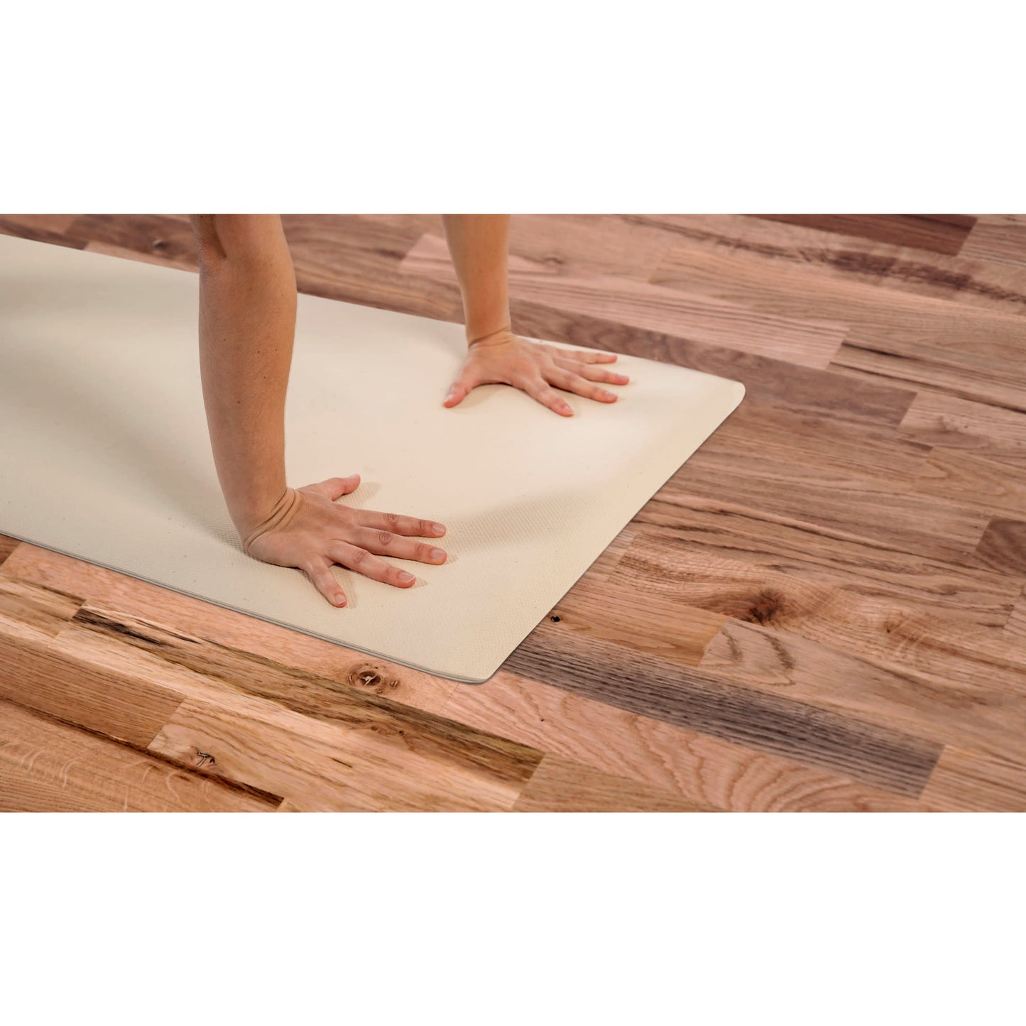 Hands press on a yoga mat on wooden floor during exercise or stretching.
