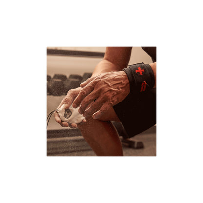 Hands apply chalk, preparing for weightlifting in the gym.