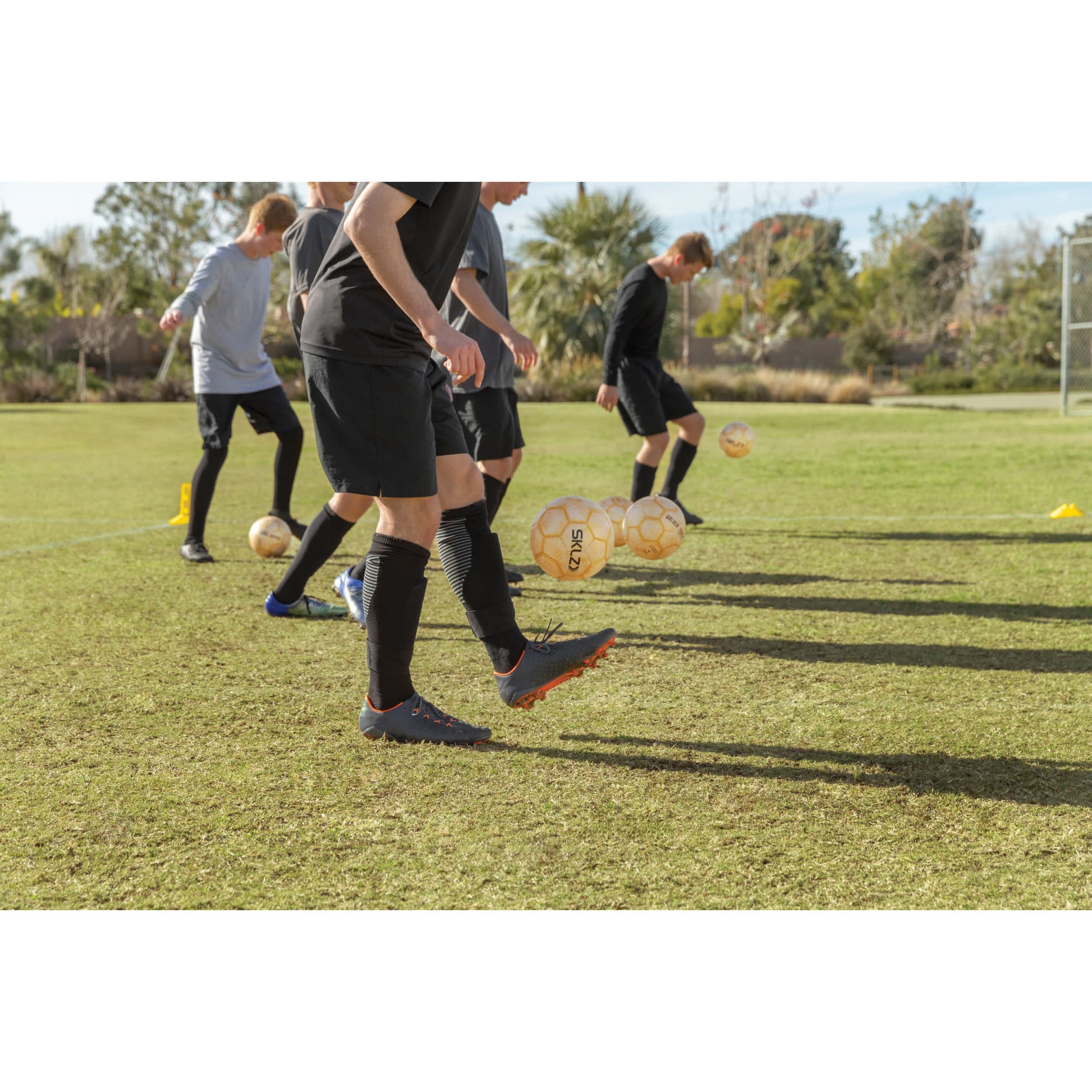 Group of boys practicing soccer drills on a field during daytime