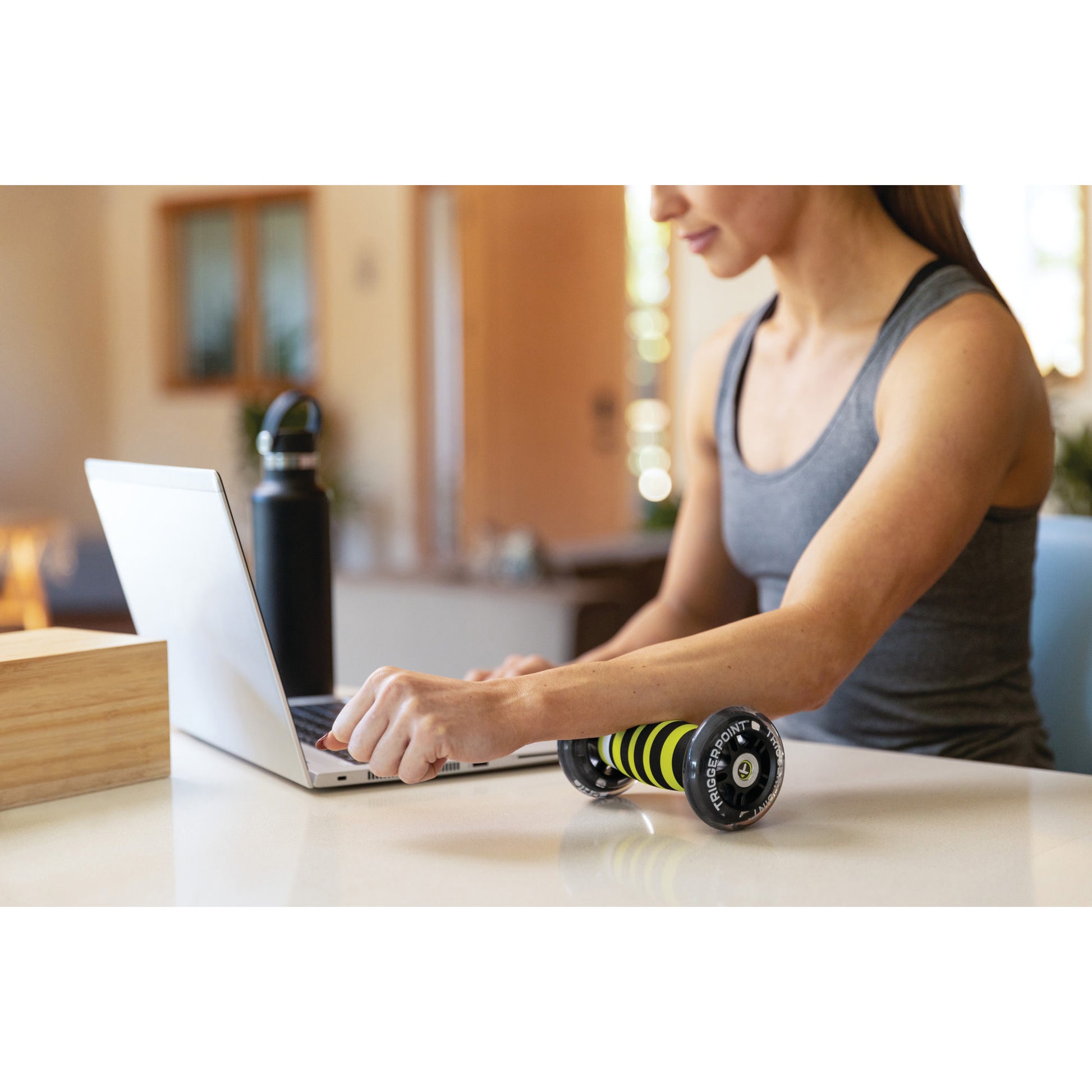 Woman using a laptop with a roller on a kitchen counter in a home environment