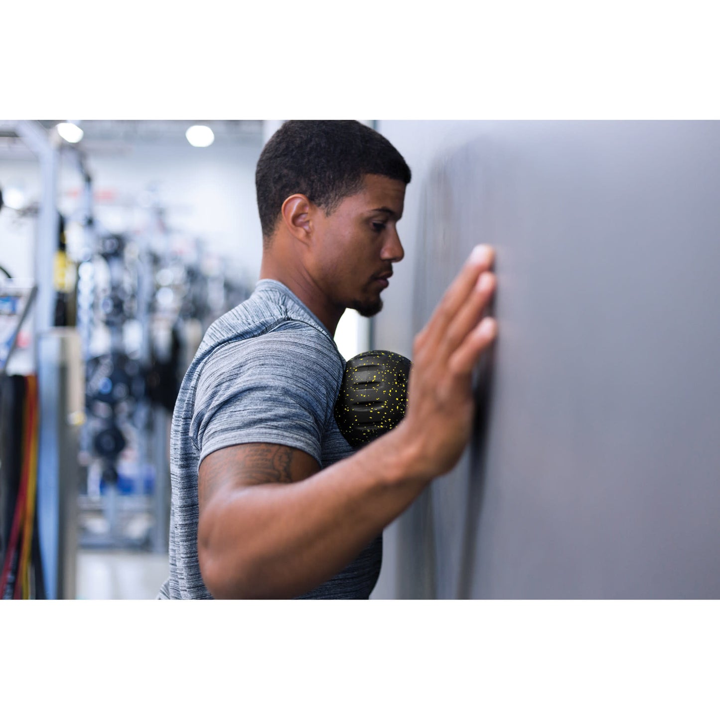 Man presses against wall with his hand during workout at gym