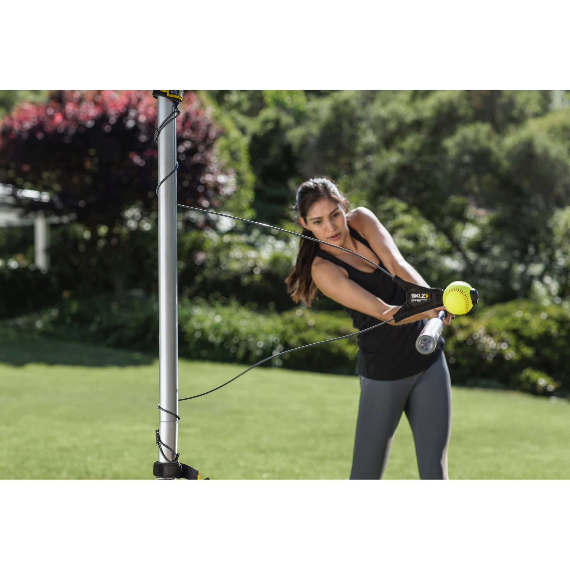 Woman exercises with resistance bands outdoors in a garden setting.