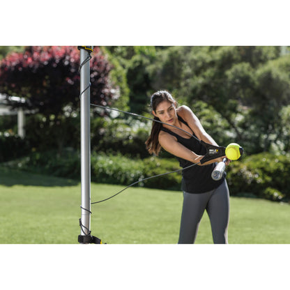 Woman exercises with resistance bands outdoors in a garden setting.
