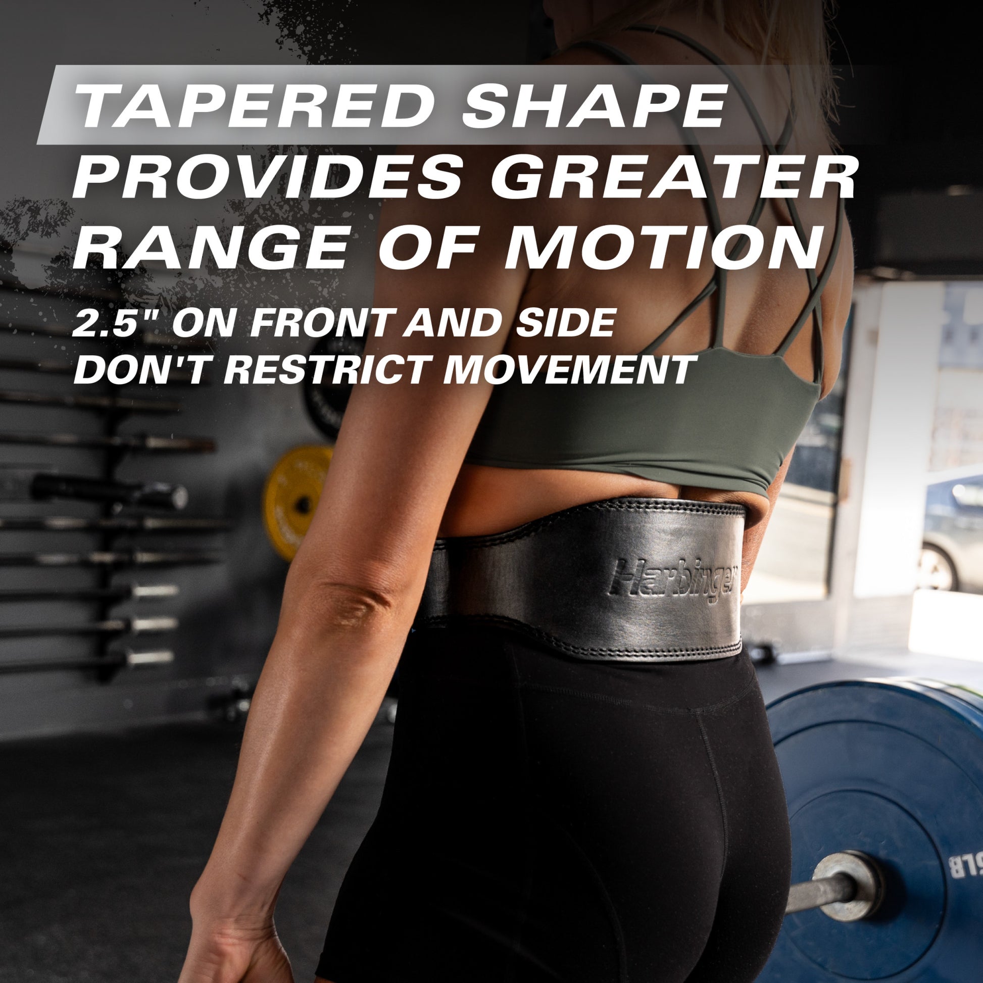 A person wears a weight belt at a gym, demonstrating its tapered shape designed for greater motion flexibility.