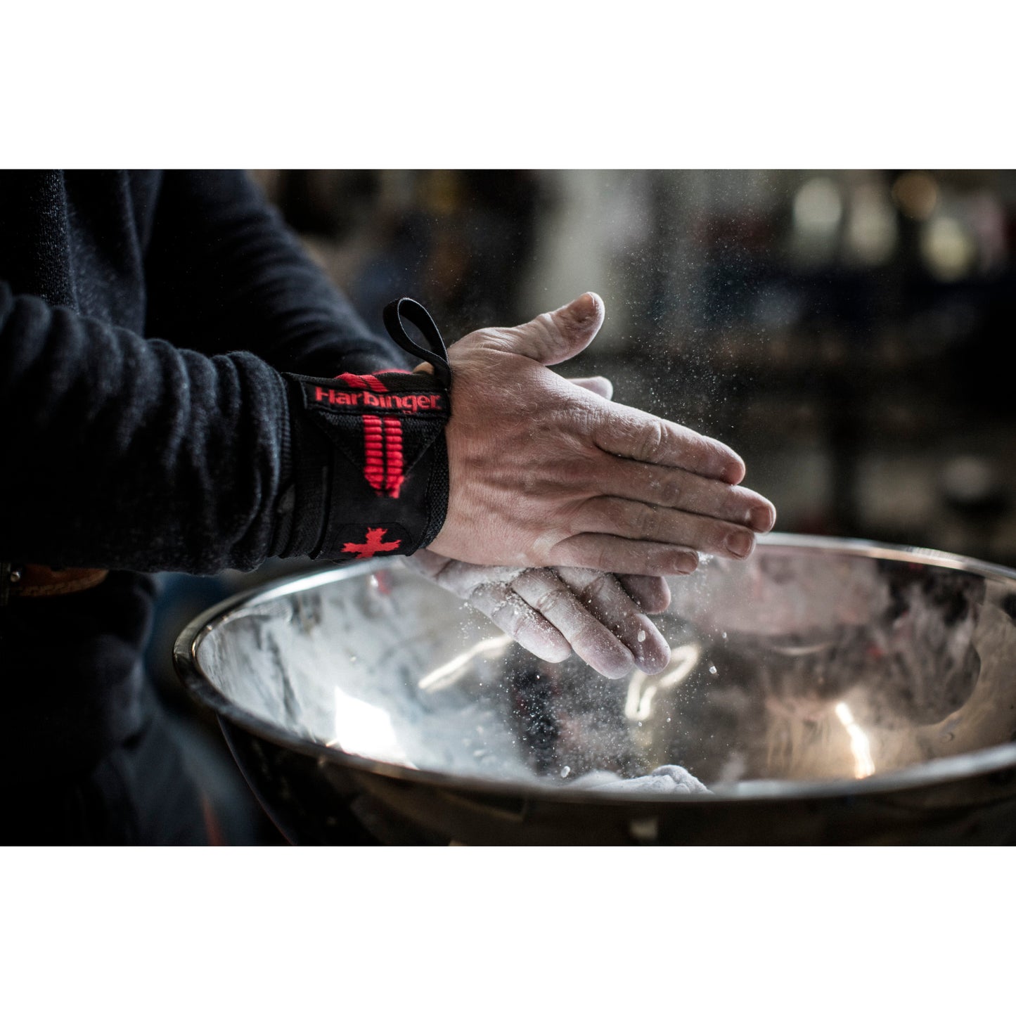 Hands rub chalk powder in a gym, with a large metal bowl below.