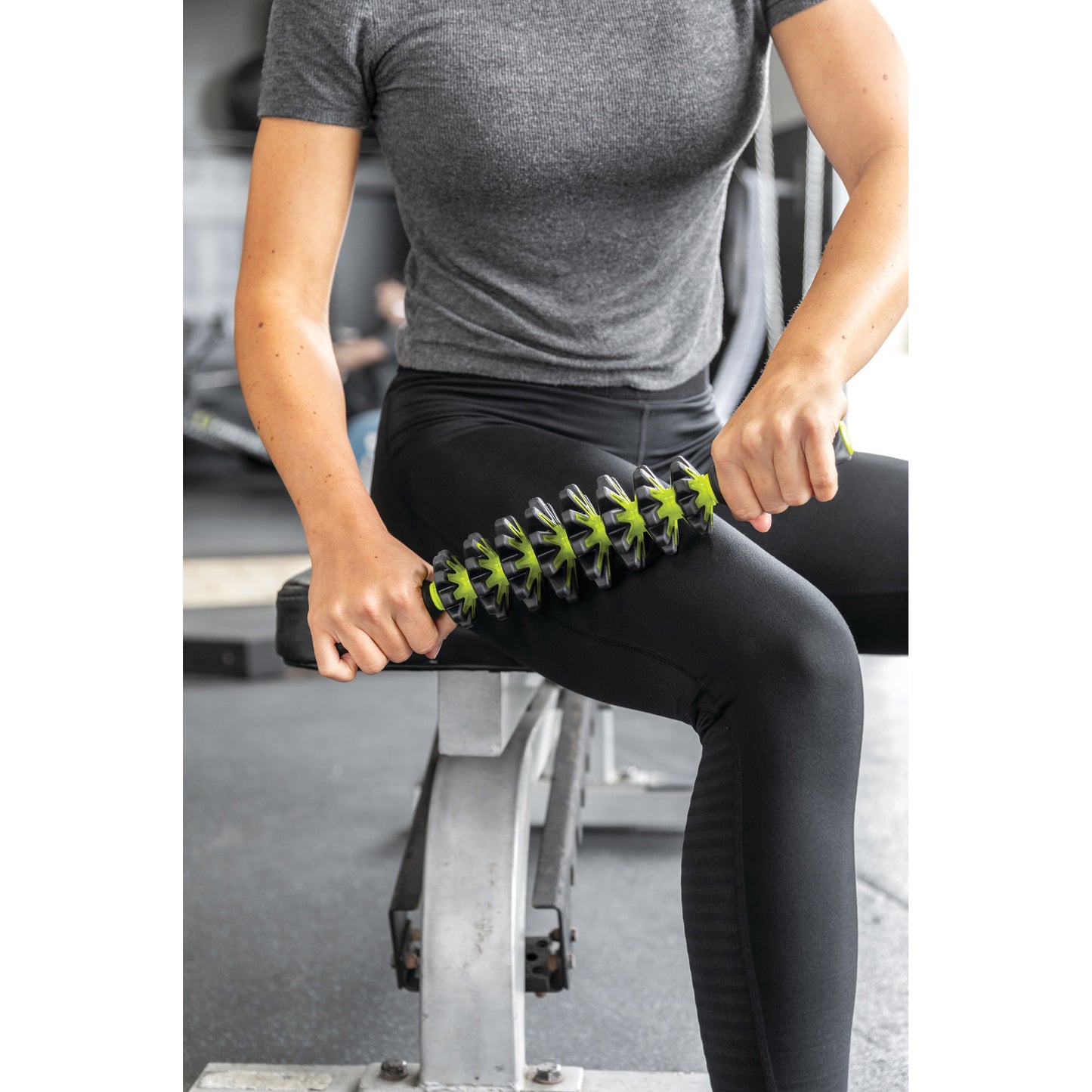 Person uses a massage roller on thigh at gym for muscle relief