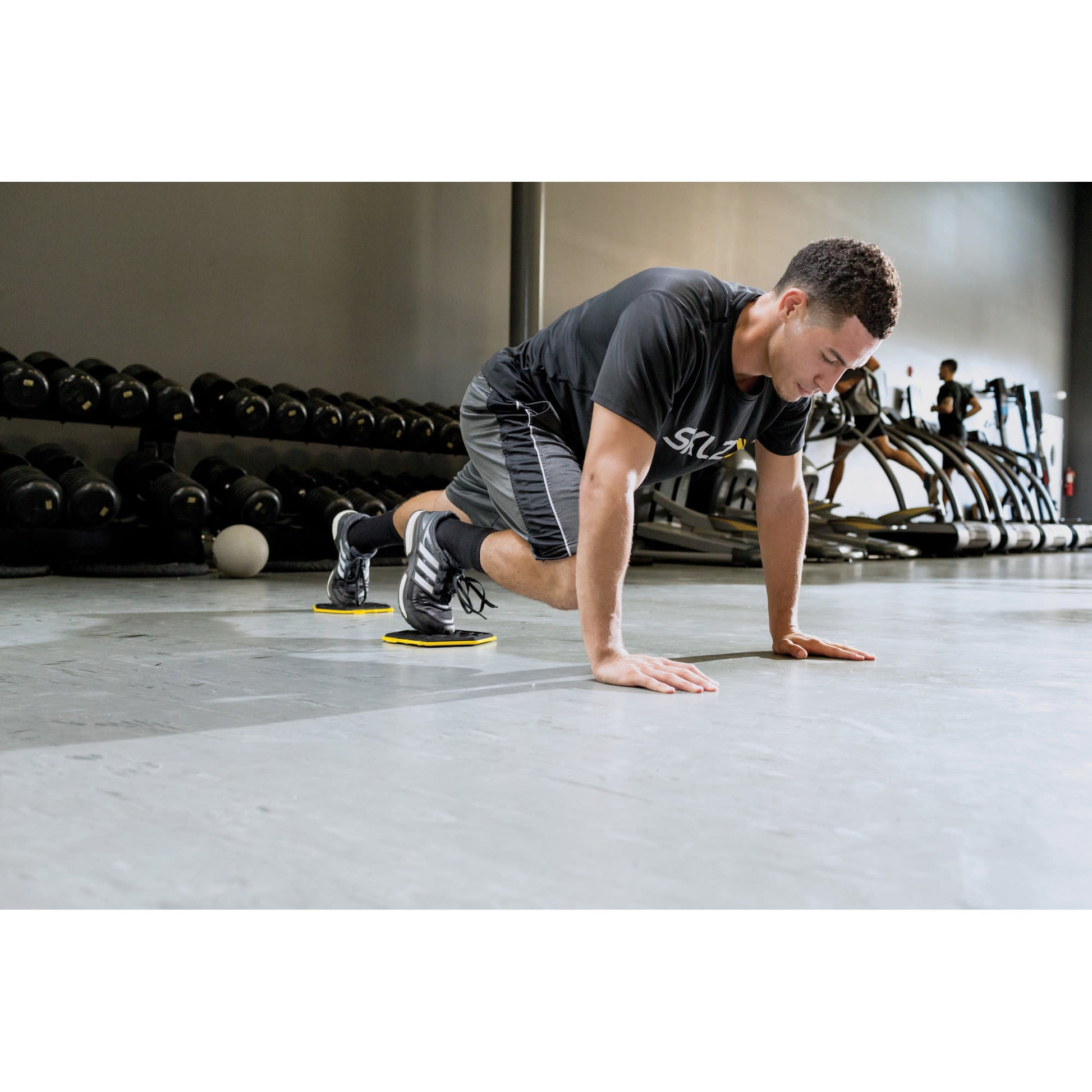 A man performs an agility drill with disk markers in a gym environment