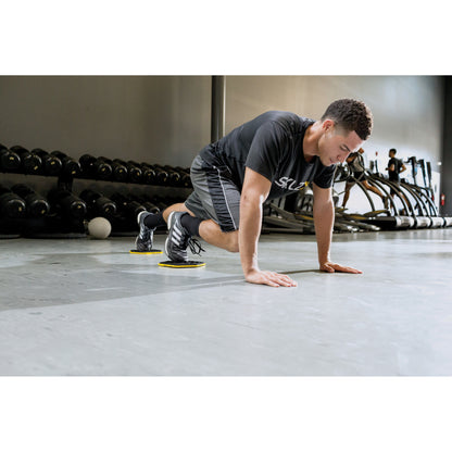A man performs an agility drill with disk markers in a gym environment
