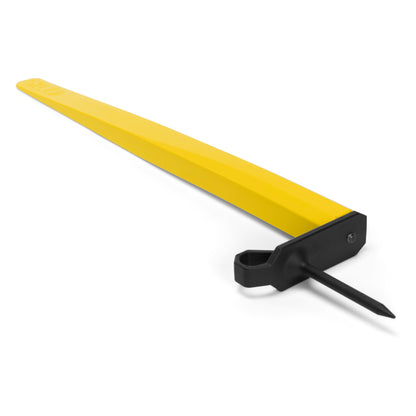 Yellow wheel chock block, lying on white surface with attached black spike.