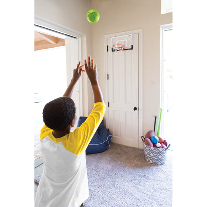 Child throws ball towards basketball hoop for indoor play