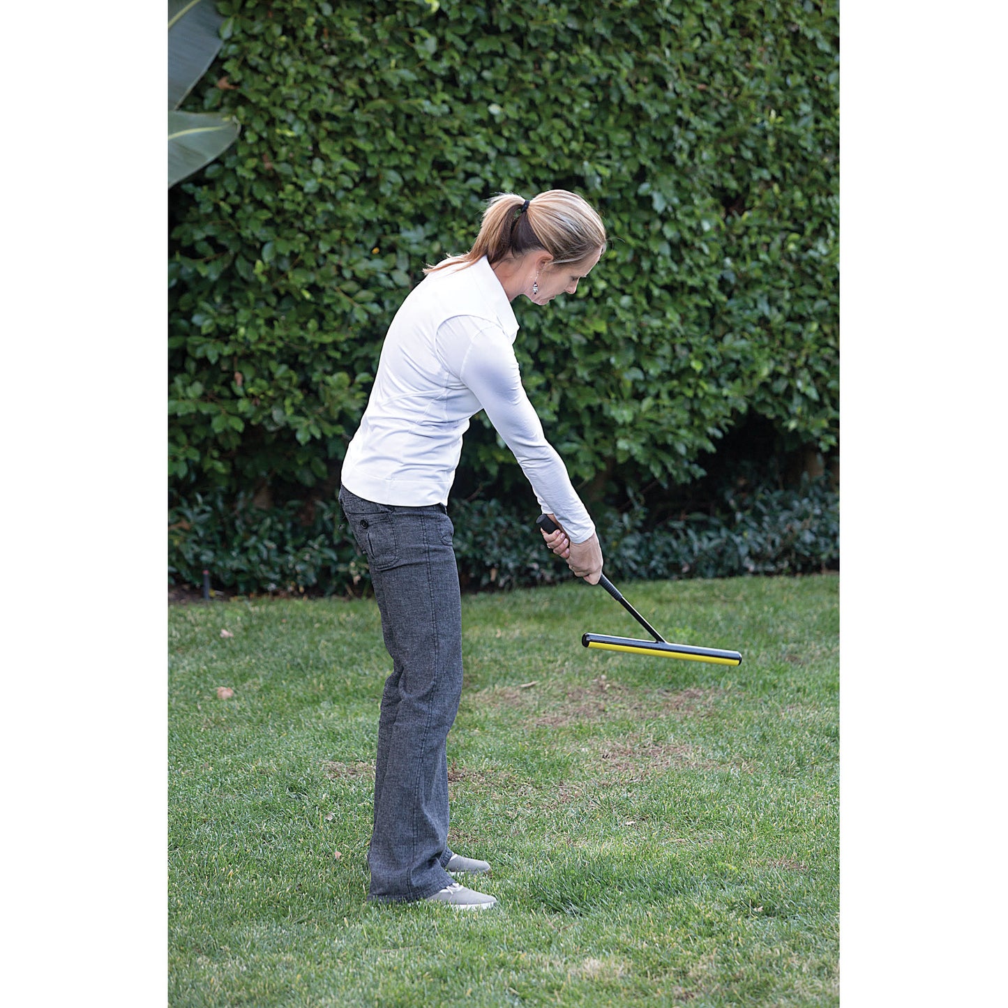 Woman practices golf putting on lawn in garden area
