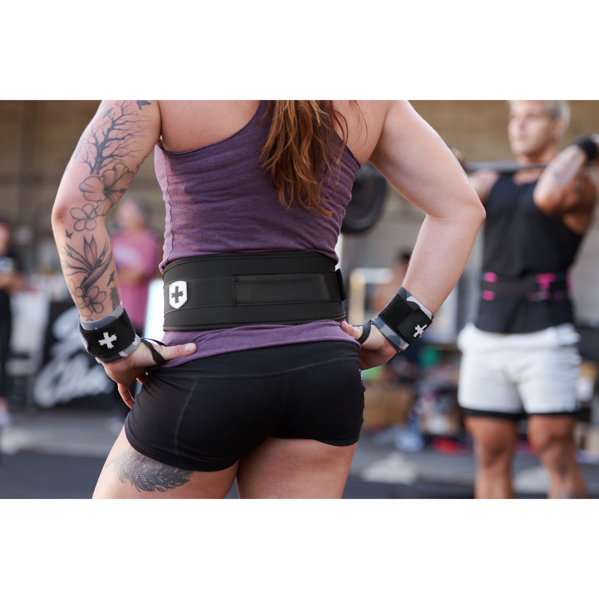 Athlete stands wearing a weight belt, preparing to lift in a gym setting.