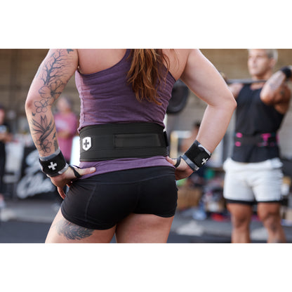 Athlete stands wearing a weight belt, preparing to lift in a gym setting.
