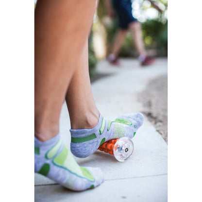 Child's foot rides roller skate on sidewalk outdoors with another child in the background