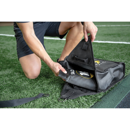 Person packs equipment into a black bag on a sports field