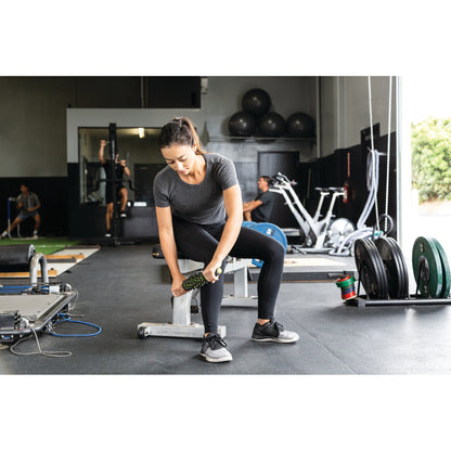 Woman exercises with a dumbbell on a gym floor surrounded by fitness equipment.