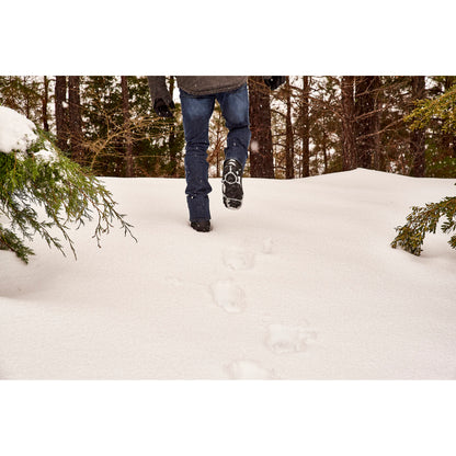 Person walks through snow in a forest during winter
