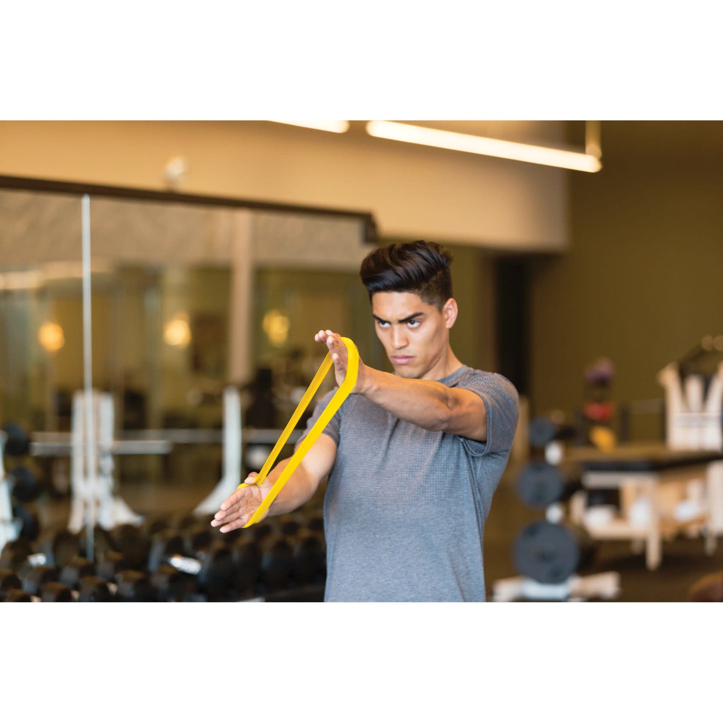 Young man stretches resistance band in gym for workout session