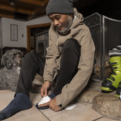 Man shoes his dog after skiing indoors with paw in shoe at home