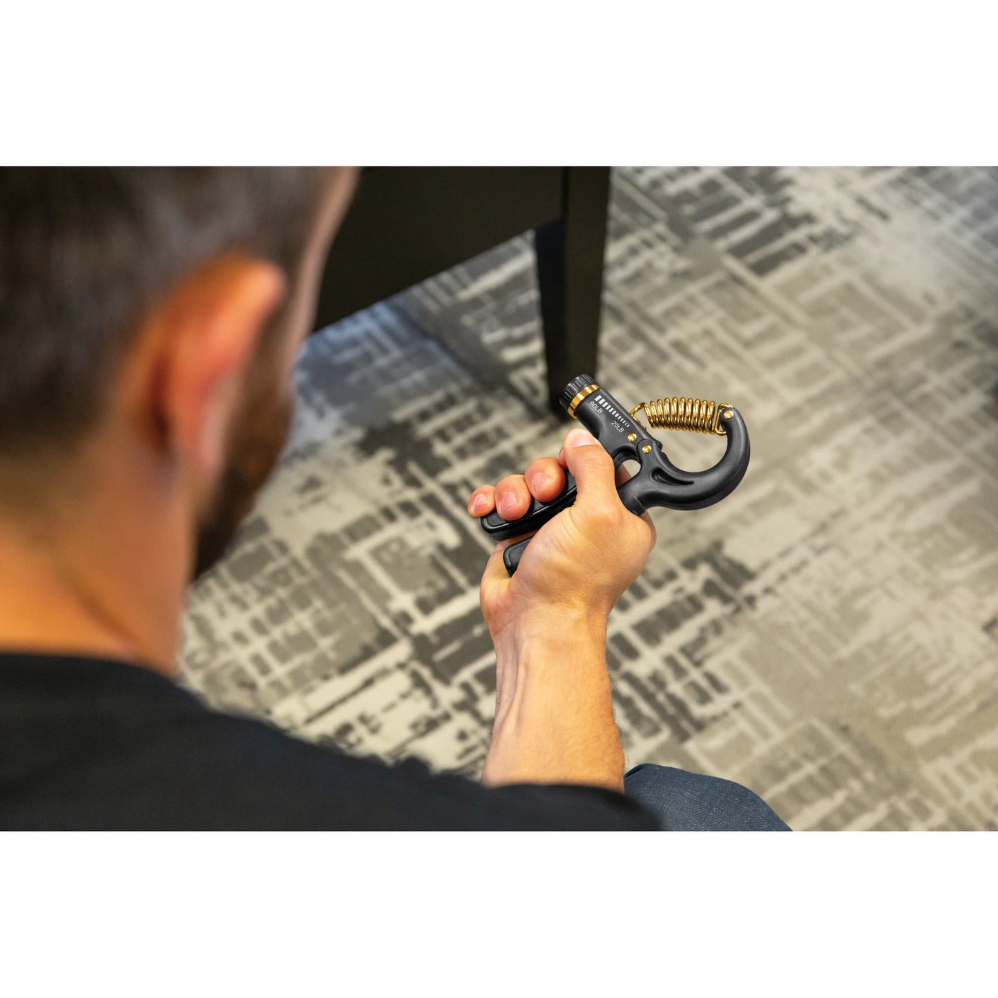 Hand holds a showerhead in a room with patterned carpet and dark furniture