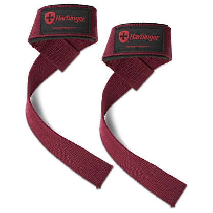 Two maroon wrist wraps tighten around hands in a gym setting for support during weightlifting.