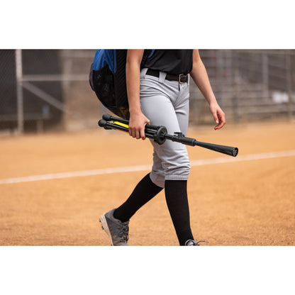 Baseball player walks on field carrying a bat during a game or practice.