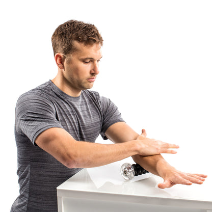 Man applies massage oil to his arm in a physiotherapy clinic setting.