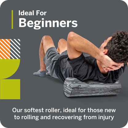 A person uses a foam roller on their back in a gym environment for muscle recovery.