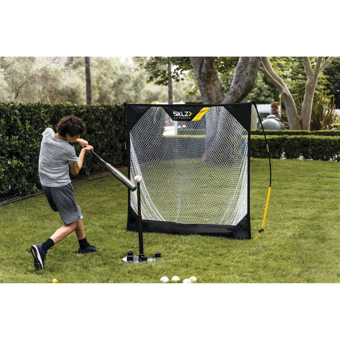 Child practices golf with a swing in front of a portable net on a grassy lawn