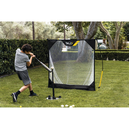 Child practices golf with a swing in front of a portable net on a grassy lawn
