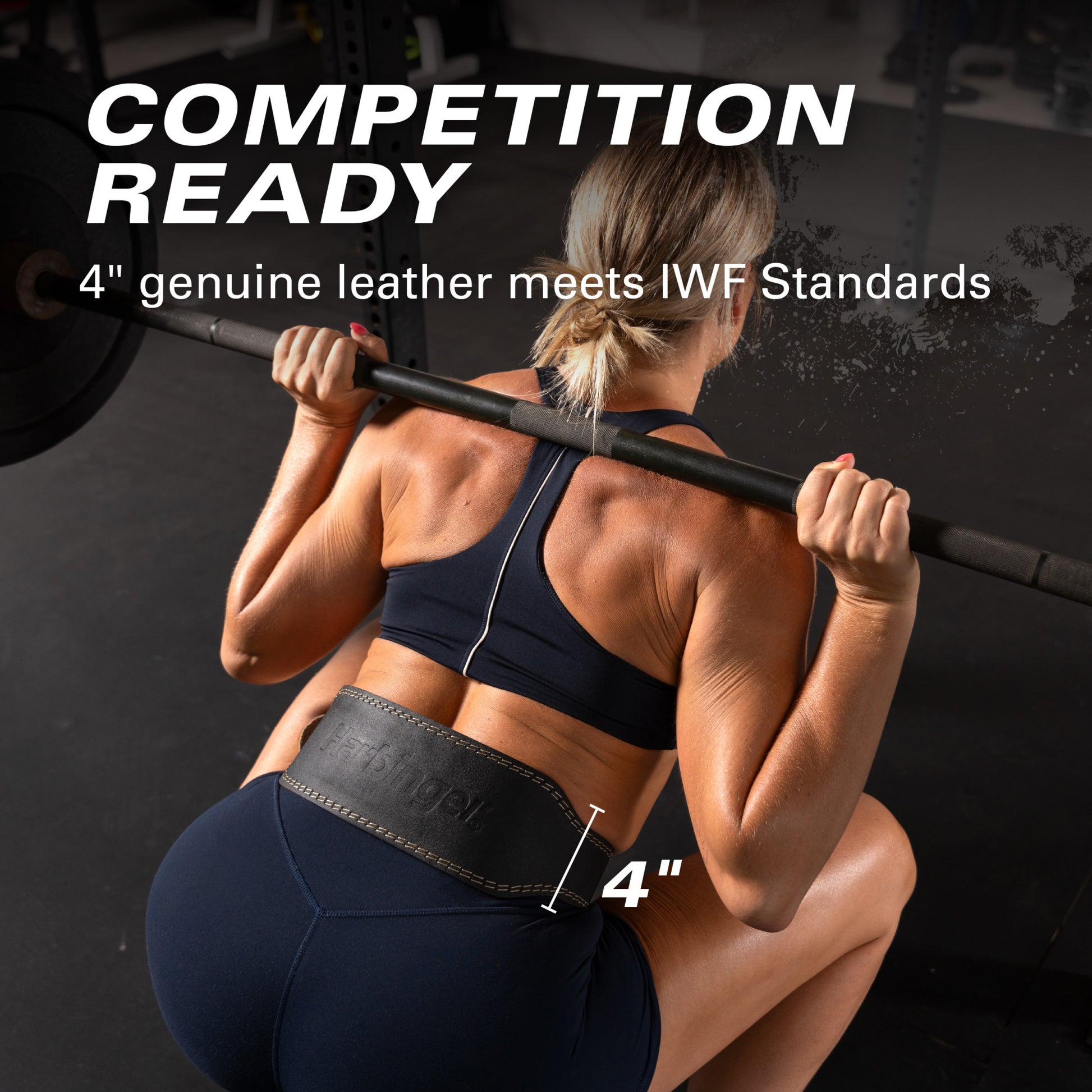 Athlete squats with barbell, wearing a leather belt in a gym setting.