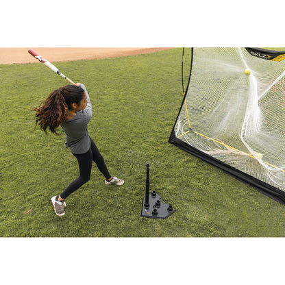 Action shot of a female hitting a ball off the SKLZ 5-position tee on a field into a net