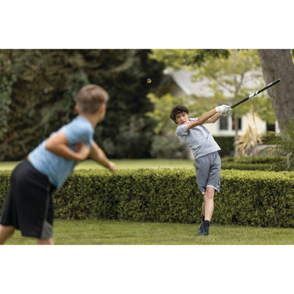 Boy swings golf club in garden while another boy watches nearby