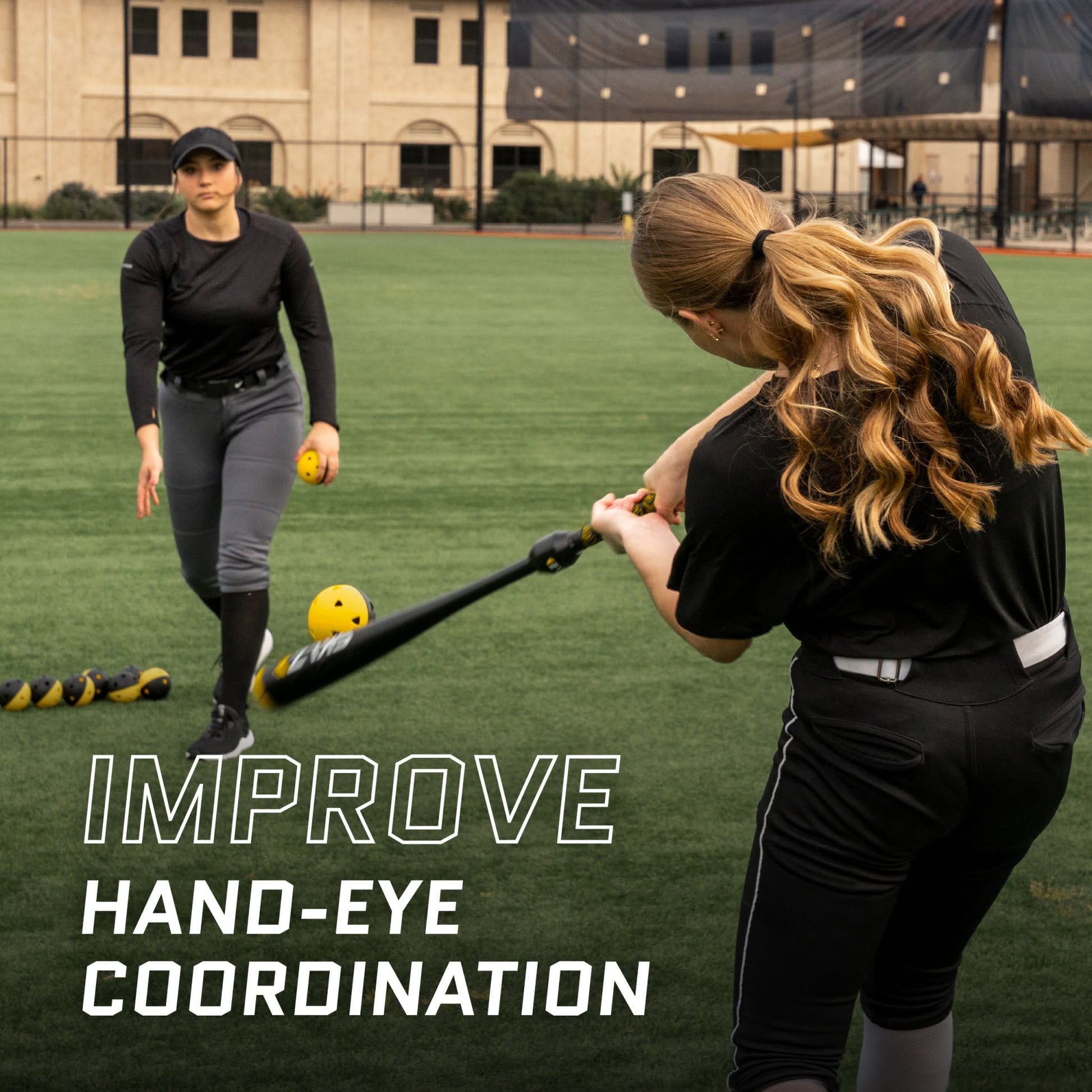 Woman practicing hitting a ball with a bat on a sports field.