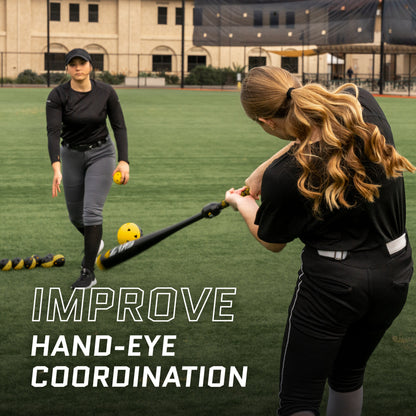 Woman practicing hitting a ball with a bat on a sports field.