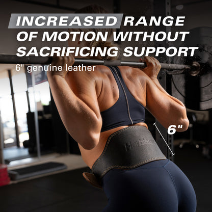 Weightlifter wears leather belt lifting barbell in gym.